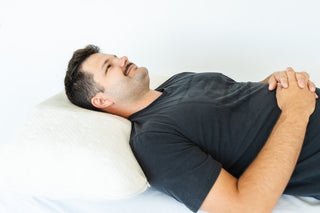 customer using crown lift in pillow demonstrating his shoulders are relaxed and even with pillow and his head and neck are comfortably supported