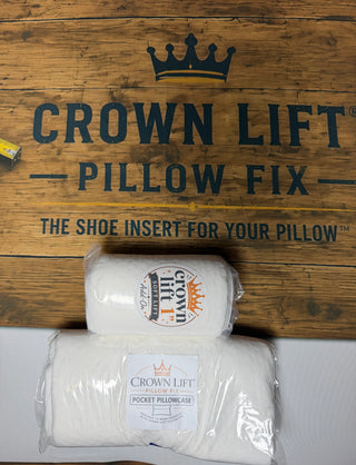 Two packaged white Crown Lift Pillow Fix pocket pillowcases stacked on a rustic wooden sign that reads 'CROWN LIFT PILLOW FIX' with a crown logo. Crown Lift starter kit comes with the signature pocket pillowcase and one one inch SOFT core lift to get you started. If you love the lift, order the full system and get $10 OFF plus FREE shipping