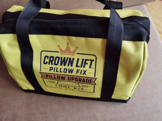 A yellow and black tool kit bag with the brand 'Crown Lift Pillow Fix' printed on the front, resting on a neutral surface. Actual color of the tool bag, yellow.