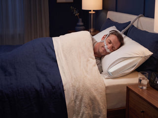 man lying in bed using his cpap with a 2" crown lift inside his pillow.